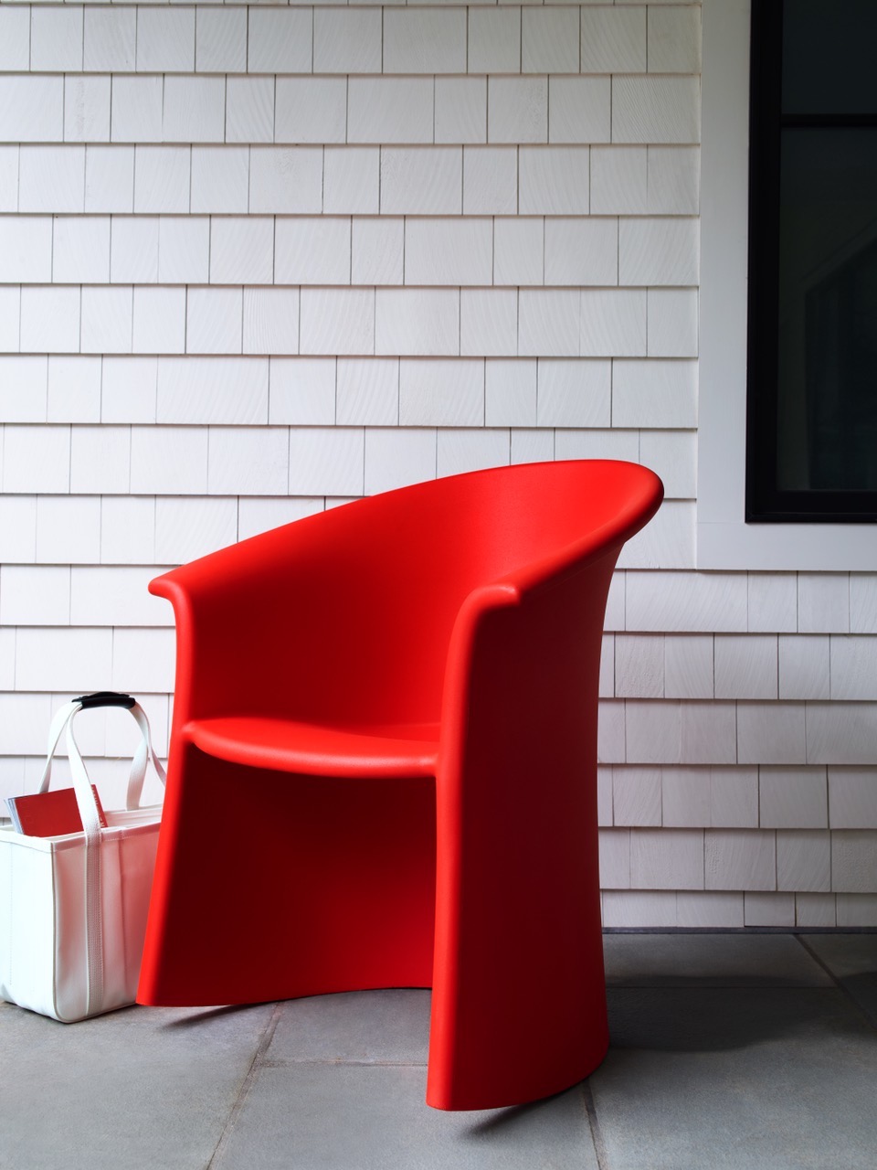 a bright red designer rocking chair on a porch.