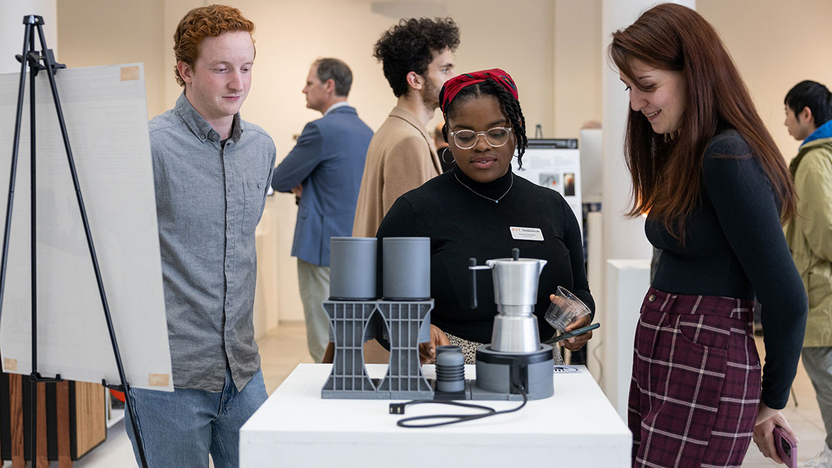 students looking at a coffee carafe and mug set as an art exhibition.