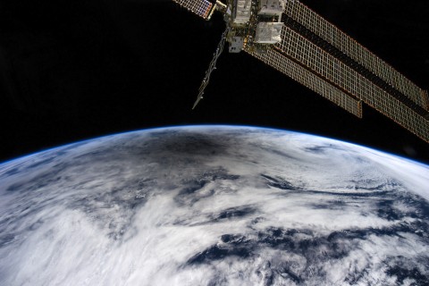 View of hazy white cloud forms over the curvature of earth with from space station. Black sky.