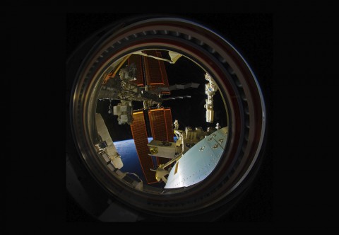 View of planet earth through round portal window on space station.