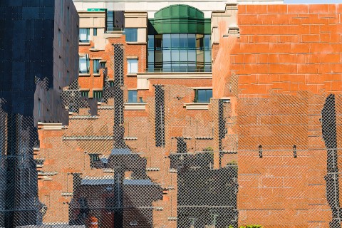 Manipulated and abstracted photographic image of collaged image of pieces of buildings - window grids, metal mesh fencing, and brick walls