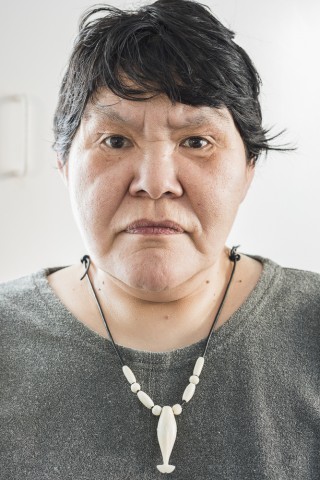 Close up full front view of a woman's face with black hair and a serious expression