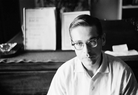 Black and white photo portrait of musician Bill Evans wearing glasses, a short haircut and white collared shirt