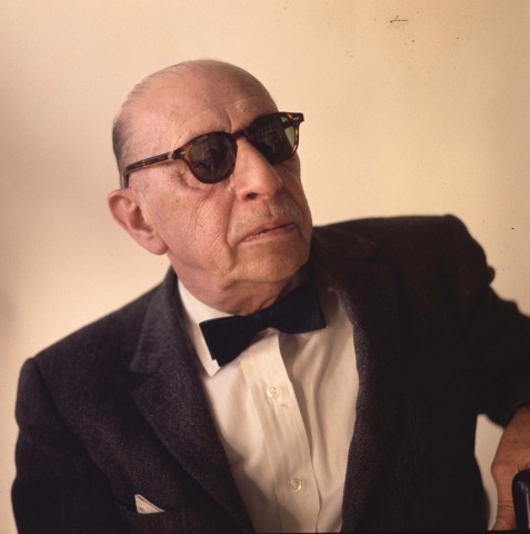 Color photo portrait of Igor Starvinsky wearing dark glasses, a black suit coat and bow tie