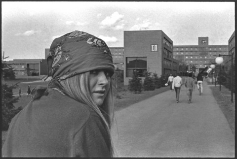 View of a young woman wearing a head bandana looking back over her shoulder at the photographer.