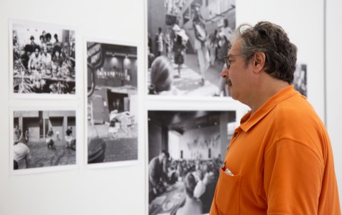 Man in bright orange shirt looking at photographs on the gallery walls