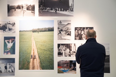 View of man looking at a collection of photographs installed on gallery walls