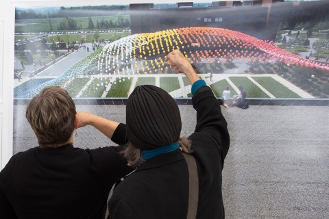 Two women looking closely at large scale color image of a balloon installation on the RIT campus
