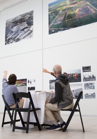 Two people seated at a table viewing and pointing at photographs on the gallery walls