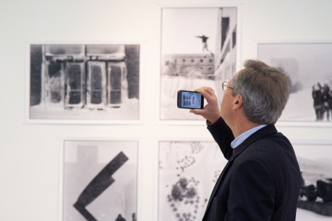 Man taking an image with a cell phone of photos on the wall