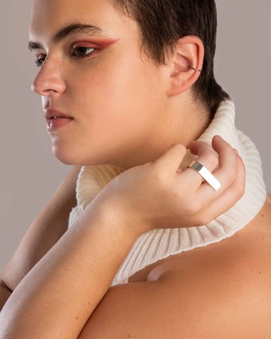 Profile of person with arm bent up toward face, wearing large silver ring