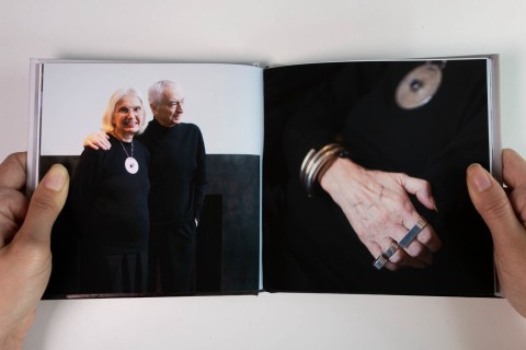 an open book with an image of Lella and Massimo Vignelli on the left, a hand with rings on the right page.