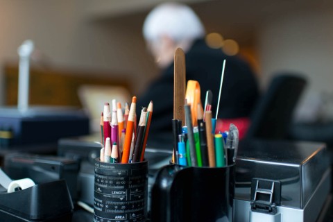 containers holding drawing and painting impliments - colorful pencils and paint brushes.
