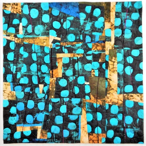 a painterly fabric quilt with bright turquoise dots on a black background sprinkled over the surface.