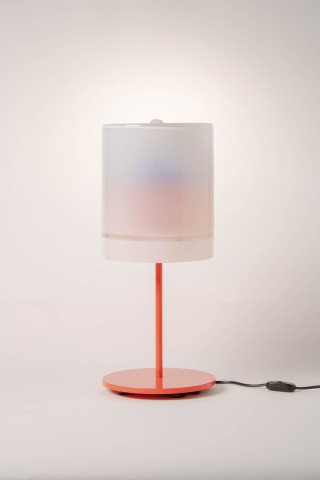 a lamp with a red metal base and glass shade against a grey background.