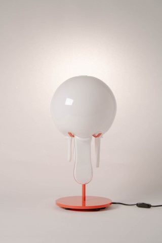 a lamp with a red metal base and glass shade against a grey background.