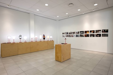 a view into the Grid Space gallery with a view of the display of lamps on wood stands.
