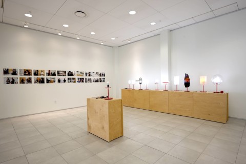 a view into the Grid Space gallery with a view of the display of lamps on wood stands. 