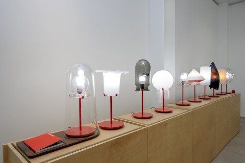 a view into the Grid Space gallery with a view of the display of lamps on wood stands.