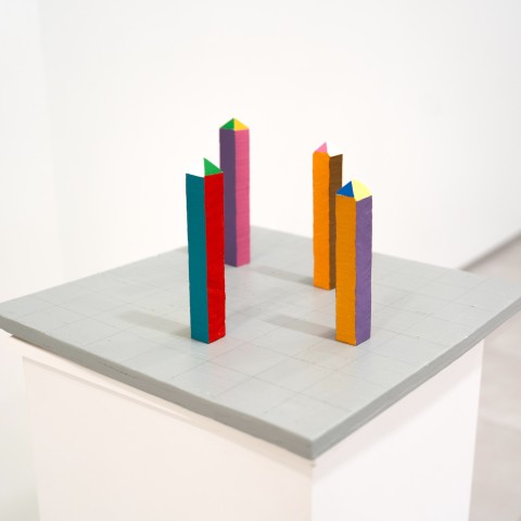 a square horizontal grey panel with a grid and colorful game board like pieces arranged on the surface.