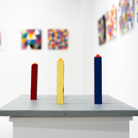 a square horizontal grey panel with a grid and colorful game board like pieces arranged on the surface. 