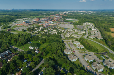 a color aerial photograph of a full landscape of a complete college campus with buildings, tree scapes and parking lots.