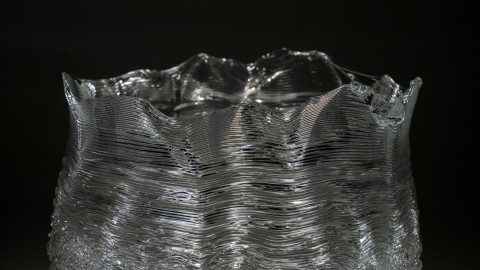 a close up of a 3D printed clear glass with a layered, undulating surface.