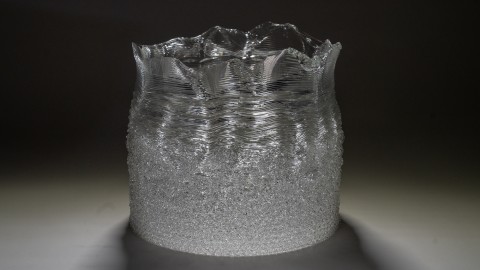 a close up of a 3D printed clear glass with a layered, undulating surface.