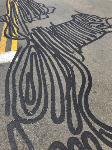 image of a portion of blacktop parking lot with patterned lines created by liquid patching tar.