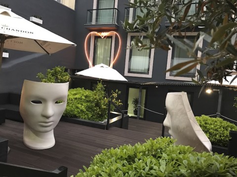 image of outdoor urban garden with two white stone sculptural heads amongst green boxwoods.
