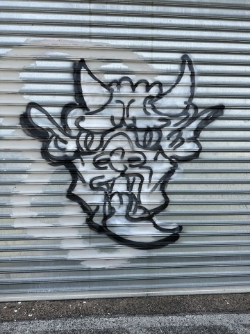 image of a graffiti drawing on a closed louvered metal door on a storefront.