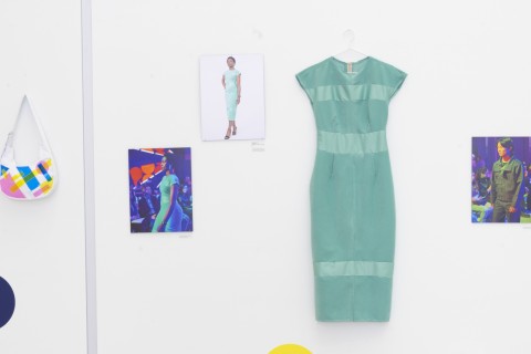 a line up of color photographs and costumes hung on a white gallery wall. 