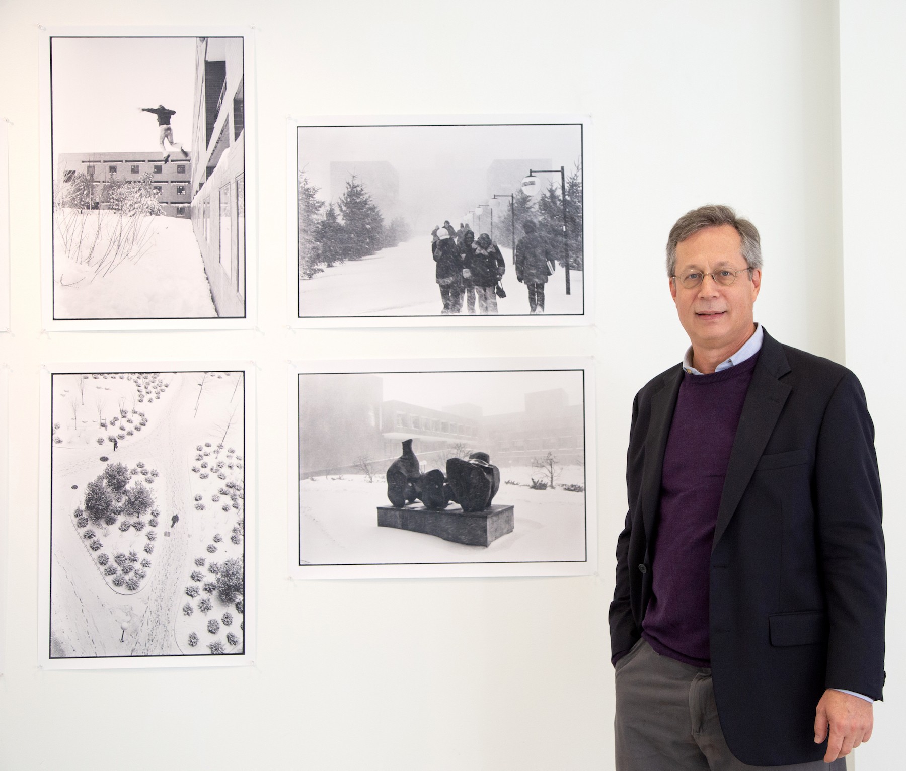 Man standing next to five large black and white photographs hung on the wall