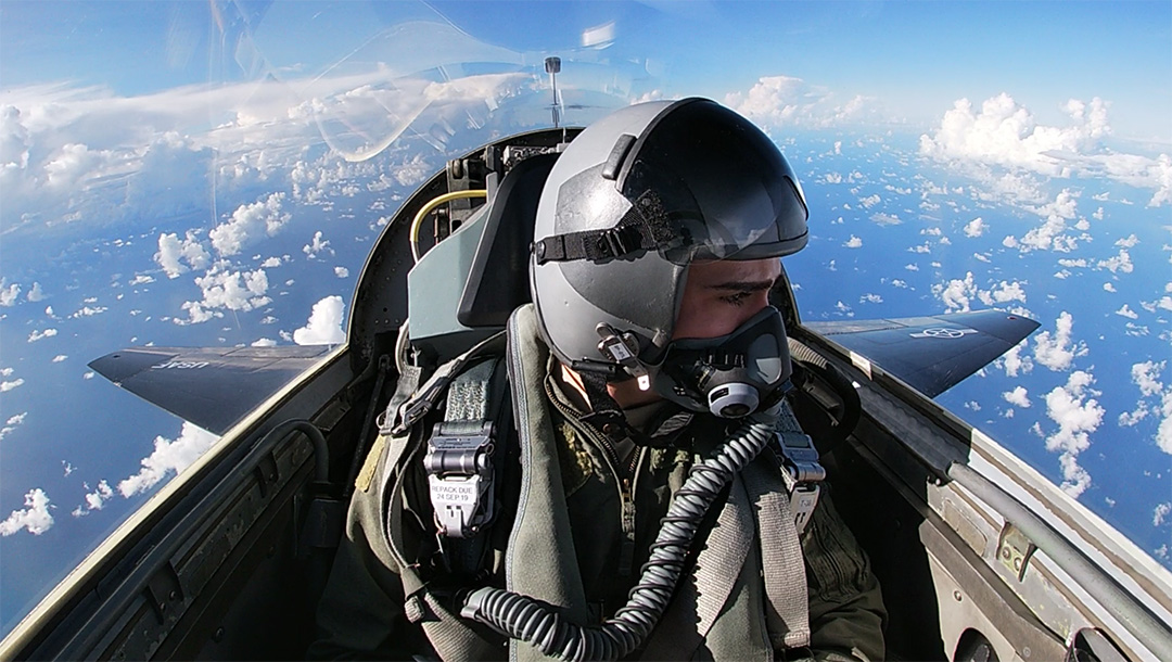 A person in a small cockpit of a jet.