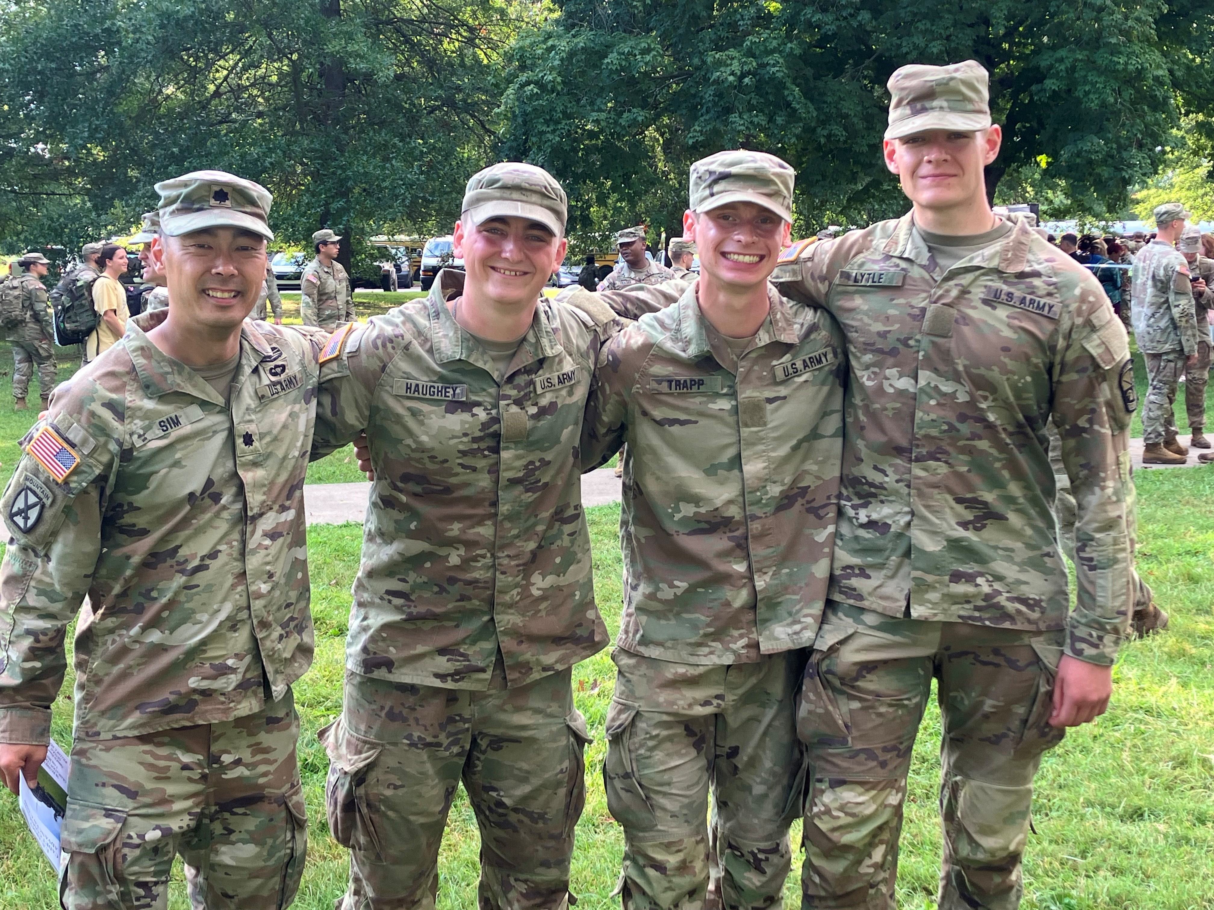 3 male cadets standing in a row, with a Lt. Col. standing to their left