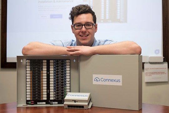 Brandon Hudson standing behind his thermostat system.