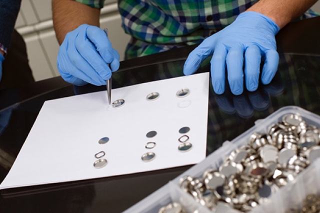 A person in gloves working with batteries.