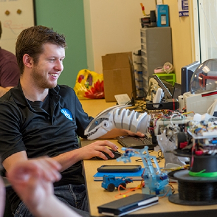 Student building robot and smiling.