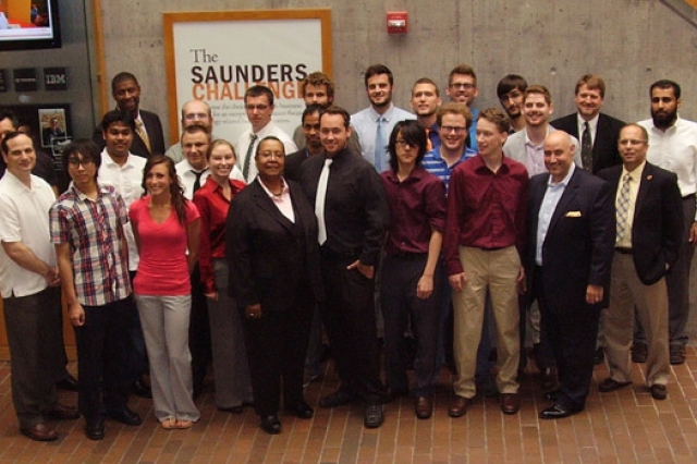 People gathered in front of "The Saunders Challenge sign"