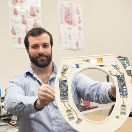 Researcher holds toilet seat with sensors attached to it.