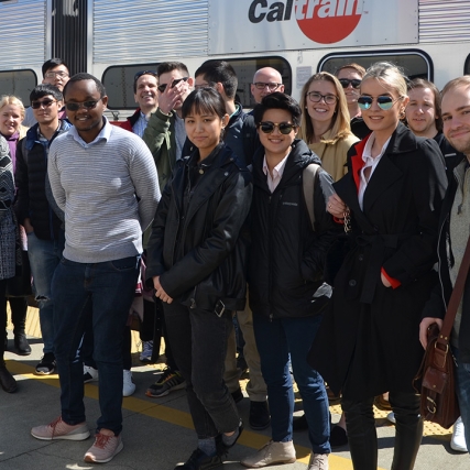Group of students stands on train platform.