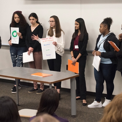 Team of high school students presents in front of group.