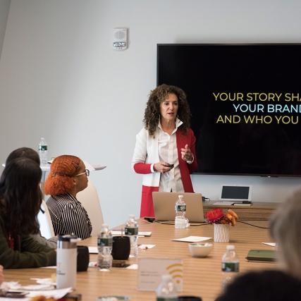 Sharon Napier stands in front of TV screen to present "Your story shapes your brand and who you are."