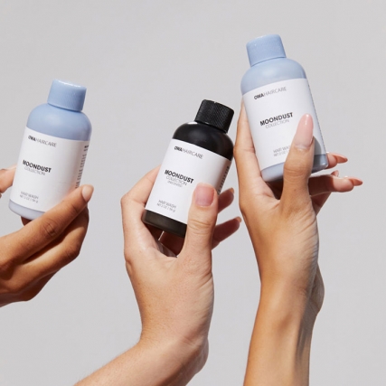 Hands holding hair-care products.