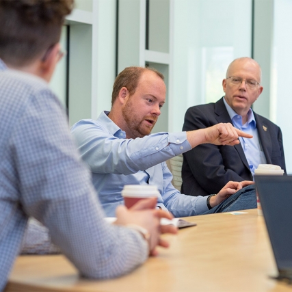 Alumnus and President David Munson talk at table with others.