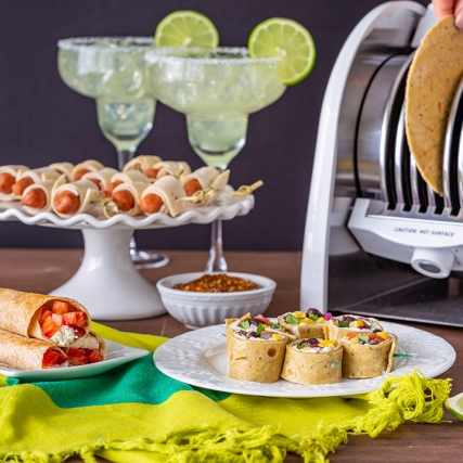 Table with tortilla toaster and platters of tortilla-based appetizers.