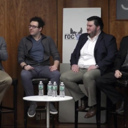 four people sitting on small stage for a panel interview.