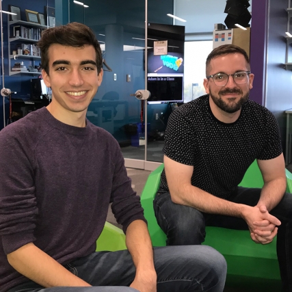 student and staff member sitting in green chairs.