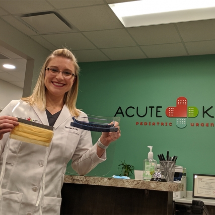 Woman holding face mask and protective shield.