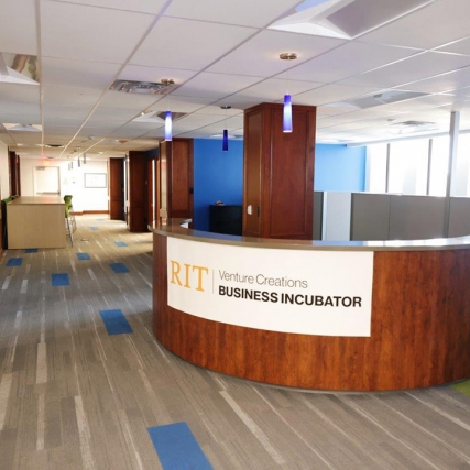 reception desk in an office area with a sign that reads: RIT Venture Creations Business Incubator.